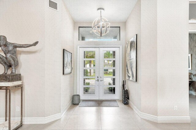 foyer entrance featuring french doors, a chandelier, and light tile patterned floors