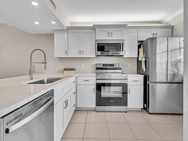 kitchen with light tile patterned flooring, stainless steel appliances, light stone countertops, sink, and ornamental molding