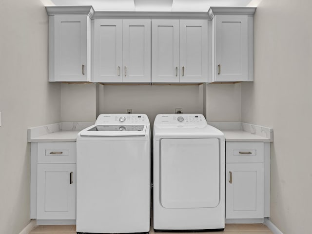 clothes washing area with cabinets and independent washer and dryer