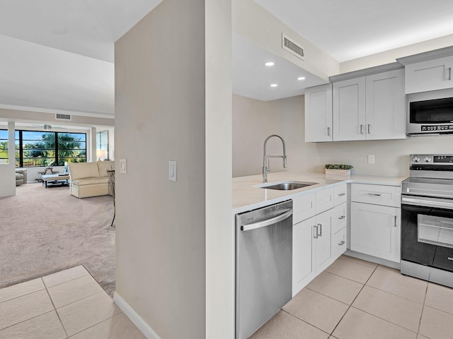 kitchen featuring stainless steel appliances, sink, light carpet, and white cabinets