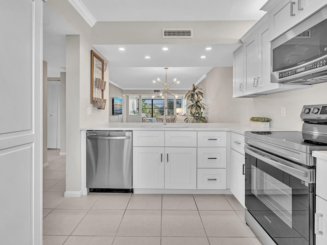 kitchen with sink, white cabinetry, stainless steel appliances, ornamental molding, and a chandelier