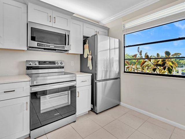 kitchen with ornamental molding, appliances with stainless steel finishes, light tile patterned floors, and white cabinets