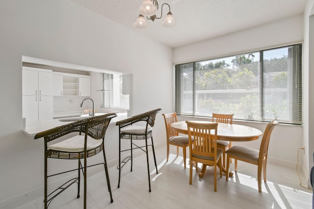 dining room featuring sink, a textured ceiling, and light hardwood / wood-style floors