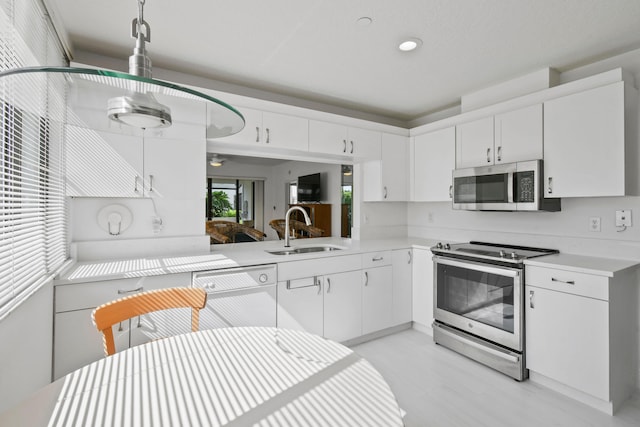 kitchen featuring appliances with stainless steel finishes, white cabinetry, and sink