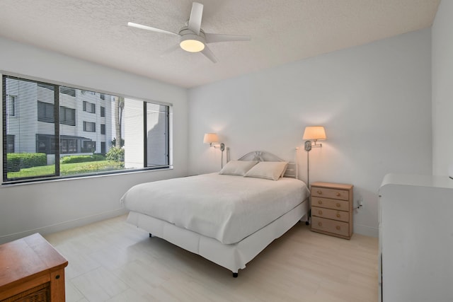 bedroom featuring light wood-type flooring, a textured ceiling, and ceiling fan