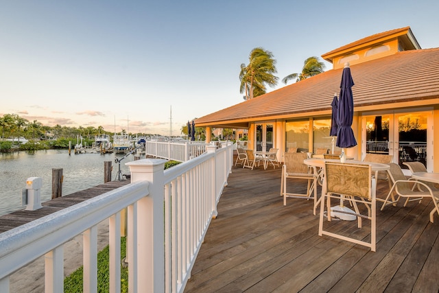 deck at dusk featuring a boat dock and a water view