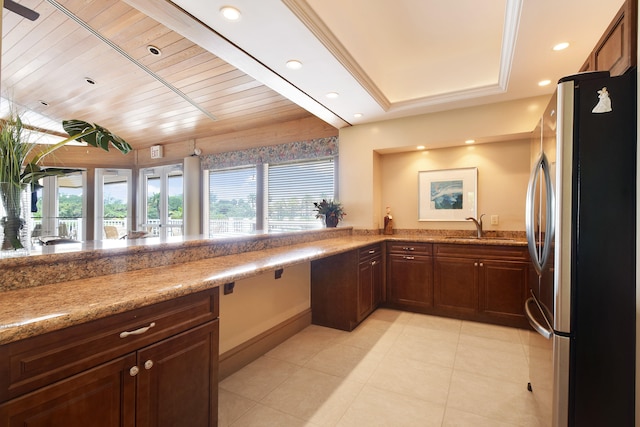 kitchen featuring sink, stainless steel refrigerator, light tile patterned floors, wooden ceiling, and a raised ceiling