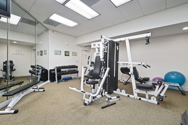 exercise room featuring carpet flooring and a paneled ceiling