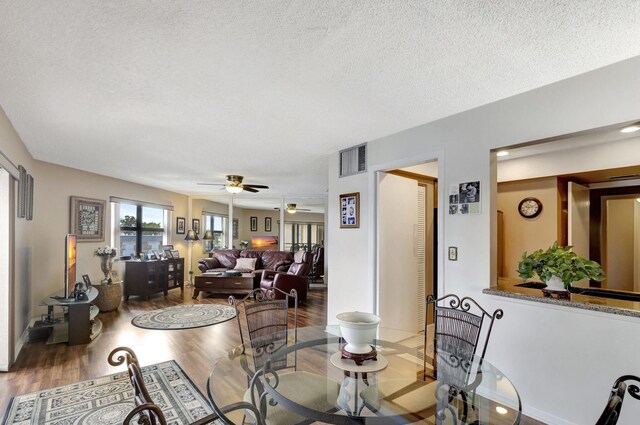 dining room with a textured ceiling, hardwood / wood-style flooring, and ceiling fan