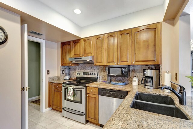 kitchen with appliances with stainless steel finishes, light tile patterned flooring, backsplash, and sink