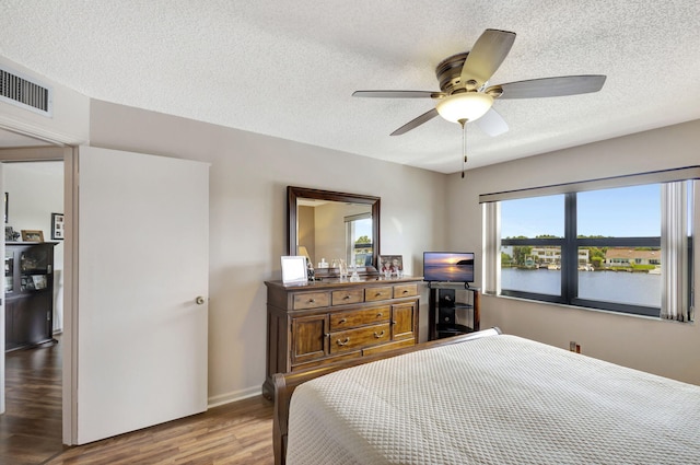 bedroom with a textured ceiling, ceiling fan, and hardwood / wood-style flooring