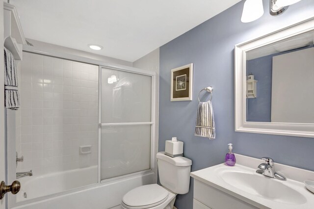 full bathroom with vanity, bath / shower combo with glass door, and toilet