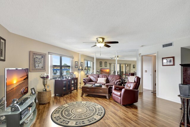 living room featuring a textured ceiling, hardwood / wood-style floors, and ceiling fan