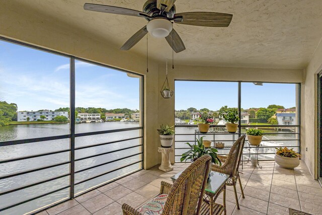 sunroom featuring a water view, ceiling fan, and plenty of natural light