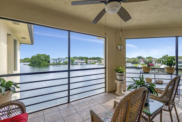 sunroom / solarium with plenty of natural light, a water view, and ceiling fan