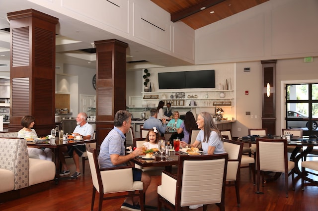 dining area featuring beam ceiling, high vaulted ceiling, decorative columns, dark hardwood / wood-style flooring, and wooden ceiling