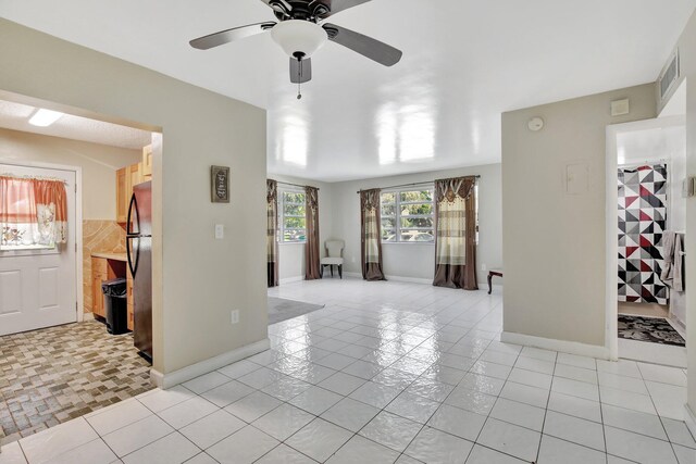 tiled empty room featuring ceiling fan