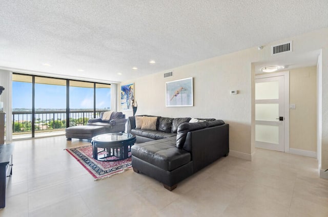 living room with a textured ceiling, light tile patterned floors, and a wall of windows