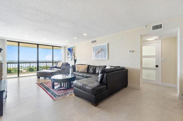 living room featuring floor to ceiling windows, visible vents, a textured ceiling, and baseboards