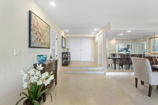 interior space with a textured ceiling, a textured wall, and recessed lighting