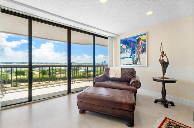 sitting room featuring a textured ceiling, a wall of windows, recessed lighting, and baseboards