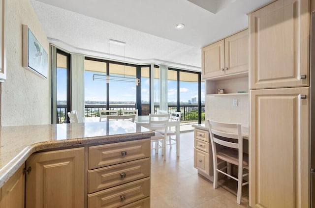 kitchen featuring light stone countertops, a wall of windows, a textured ceiling, light brown cabinets, and recessed lighting