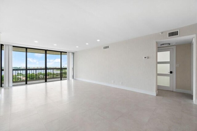 tiled empty room with floor to ceiling windows and a water view