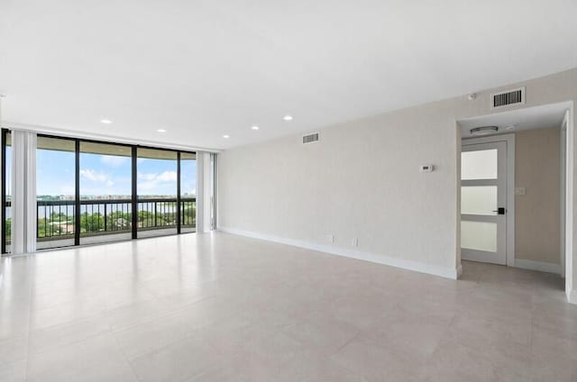 unfurnished room featuring a water view, baseboards, expansive windows, and visible vents