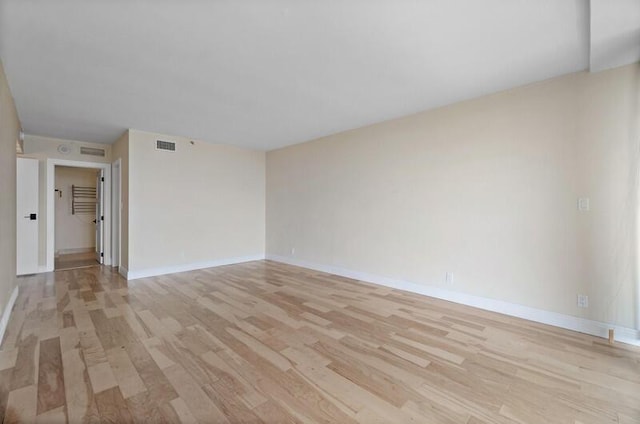 spare room with light wood-style floors, visible vents, and baseboards