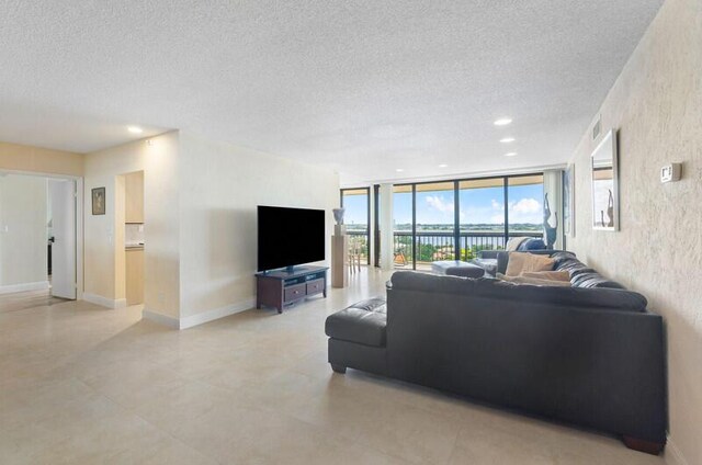 living room featuring a textured ceiling, light tile patterned floors, and expansive windows