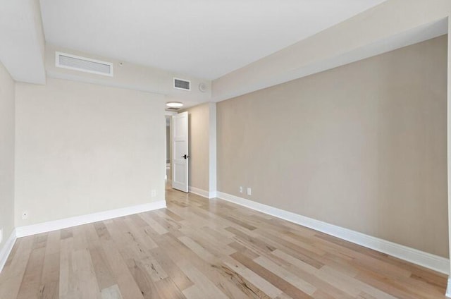 empty room with light wood-type flooring, visible vents, and baseboards