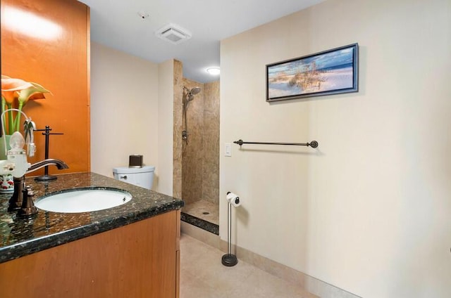 bathroom with visible vents, tiled shower, vanity, and toilet