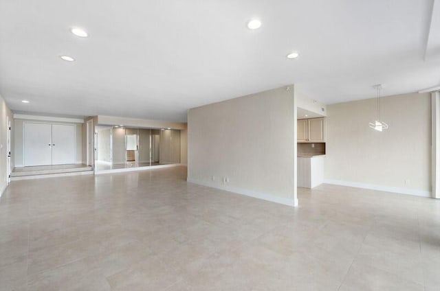 unfurnished living room with baseboards and recessed lighting