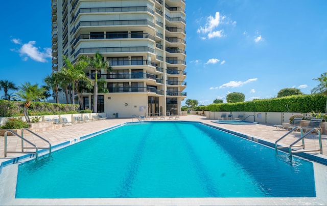 pool with a patio area, a hot tub, and fence