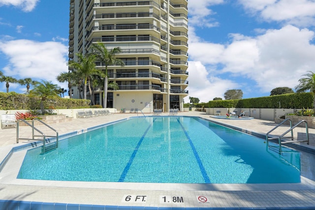 community pool with a patio area and fence