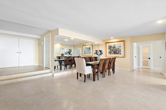 dining area with baseboards, a textured ceiling, and recessed lighting