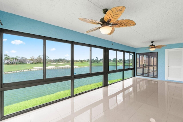 unfurnished sunroom featuring a water view and a ceiling fan