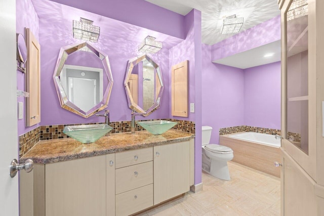 full bathroom featuring double vanity, decorative backsplash, toilet, a bath, and a sink