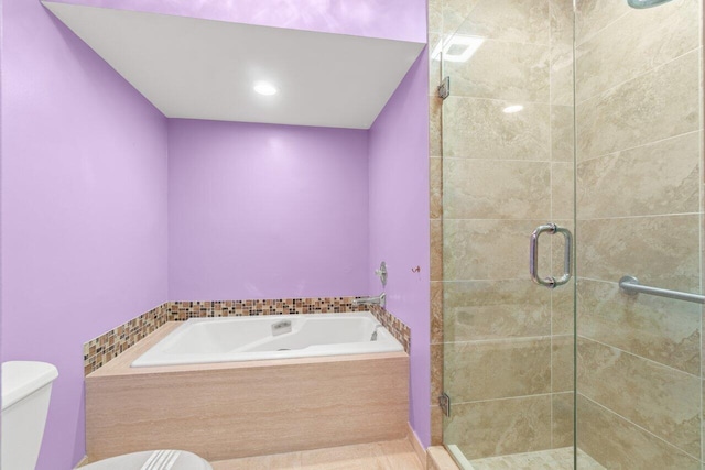 bathroom with a garden tub, a shower stall, and toilet