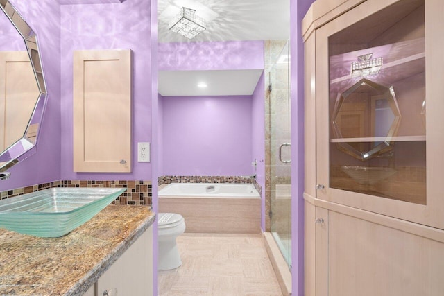 bathroom featuring a garden tub, vanity, toilet, and a shower stall