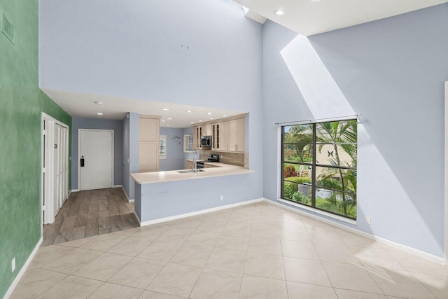 unfurnished living room with a high ceiling, baseboards, and a sink