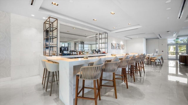 kitchen with a tray ceiling, kitchen peninsula, a breakfast bar area, and tile walls