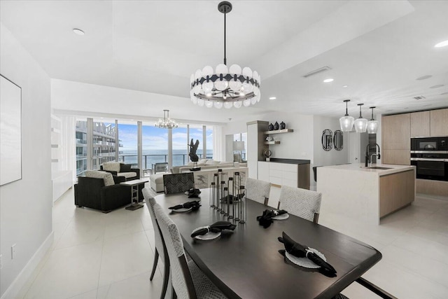 tiled dining room with a notable chandelier, sink, and a water view