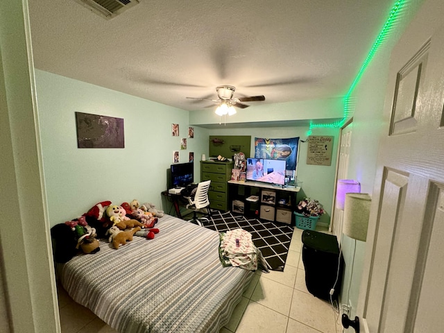 bedroom featuring a textured ceiling, ceiling fan, and light tile patterned floors