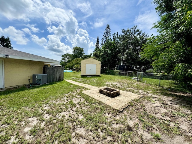 view of yard with central air condition unit, a storage shed, and a fire pit