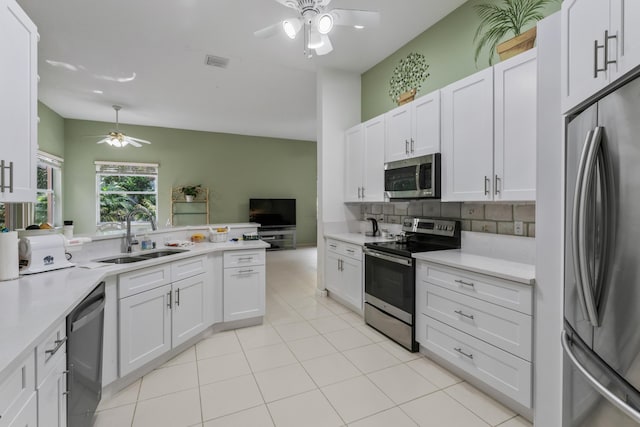 kitchen with sink, ceiling fan, appliances with stainless steel finishes, white cabinets, and decorative backsplash