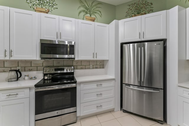 kitchen featuring tasteful backsplash, white cabinetry, appliances with stainless steel finishes, and light tile patterned floors