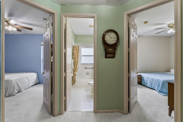 hall with light carpet and a textured ceiling