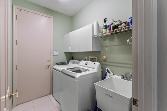 laundry area with cabinets, light tile patterned floors, sink, and washing machine and clothes dryer