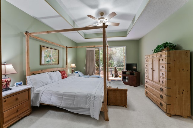 bedroom featuring ceiling fan, light colored carpet, a raised ceiling, and a textured ceiling